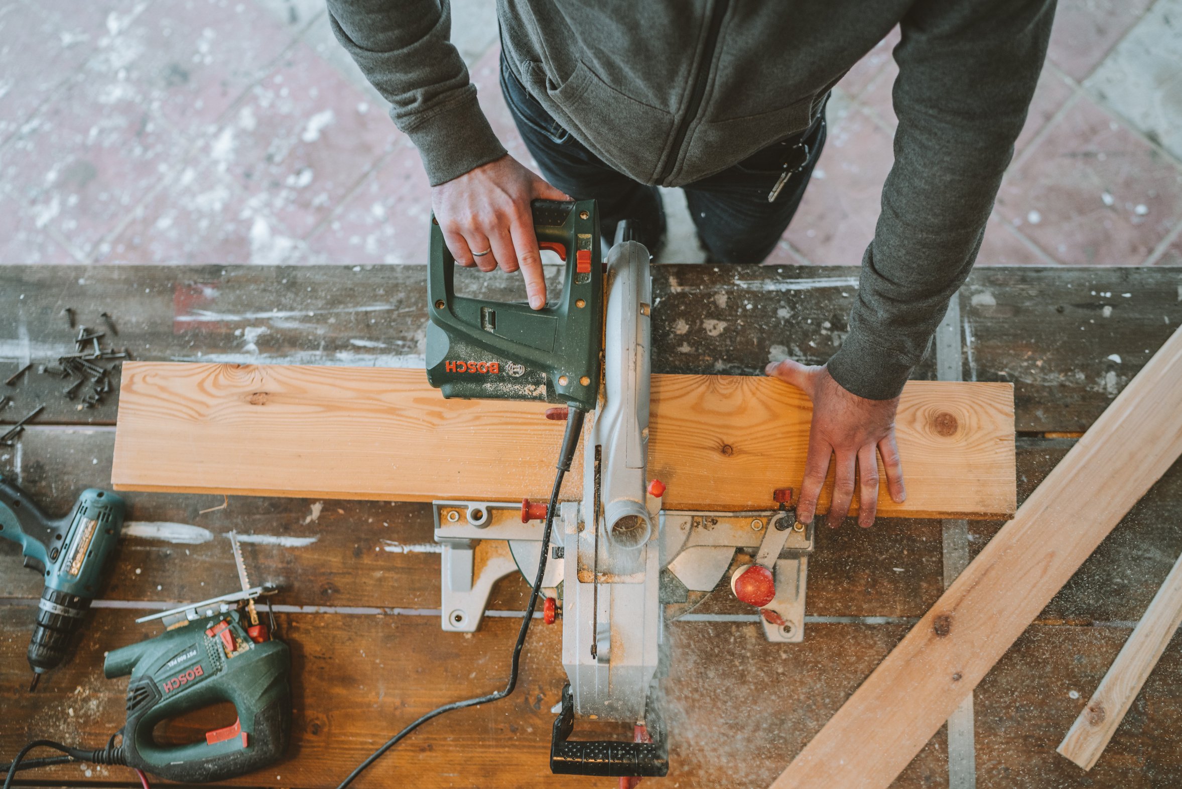 A Man Cutting Wood Using an Electric Jigsaw